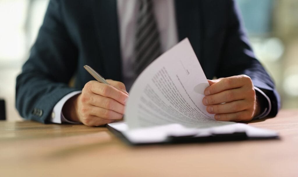 Person signing important document with pen on desk